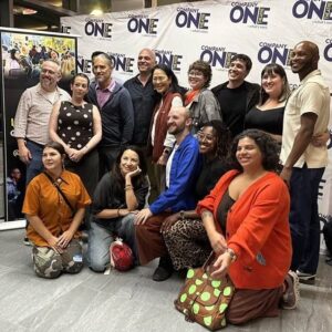 A group of people stand in front of a background that says "company one"