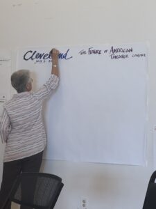 A lady faces a white piece of paper and writes the word "Cleveland"