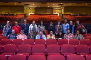 A group of people in a theater amongst red chairs
