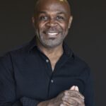 An older Black man smiles at the camera